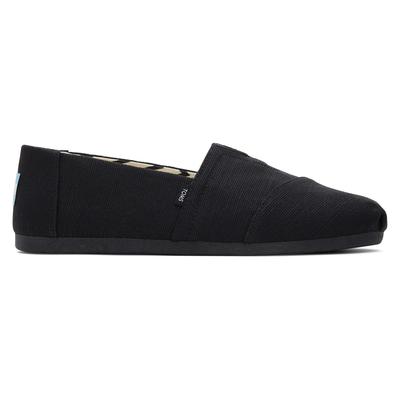 Black canvas slip-on shoes with a rounded toe, elastic gore for easy wear, and a textured fabric finish, featuring a subtle TOMS logo on the heel.