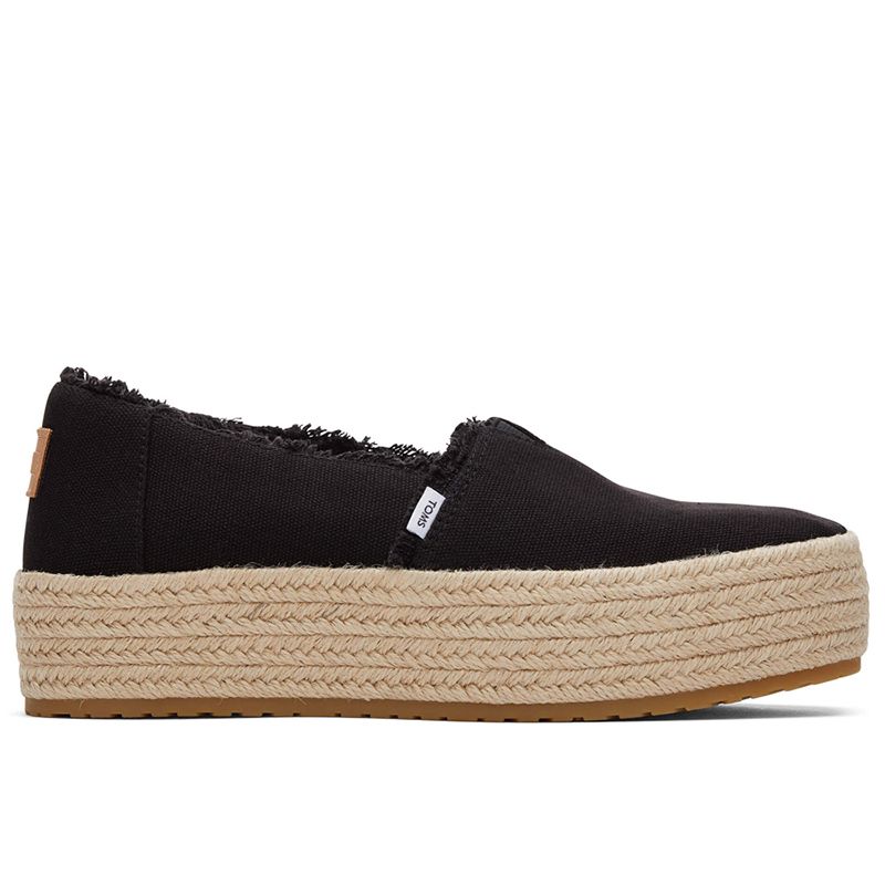 Black canvas women's espadrille slip-ons from TOMS featuring a jute rope platform sole and frayed edges for a casual, stylish look.