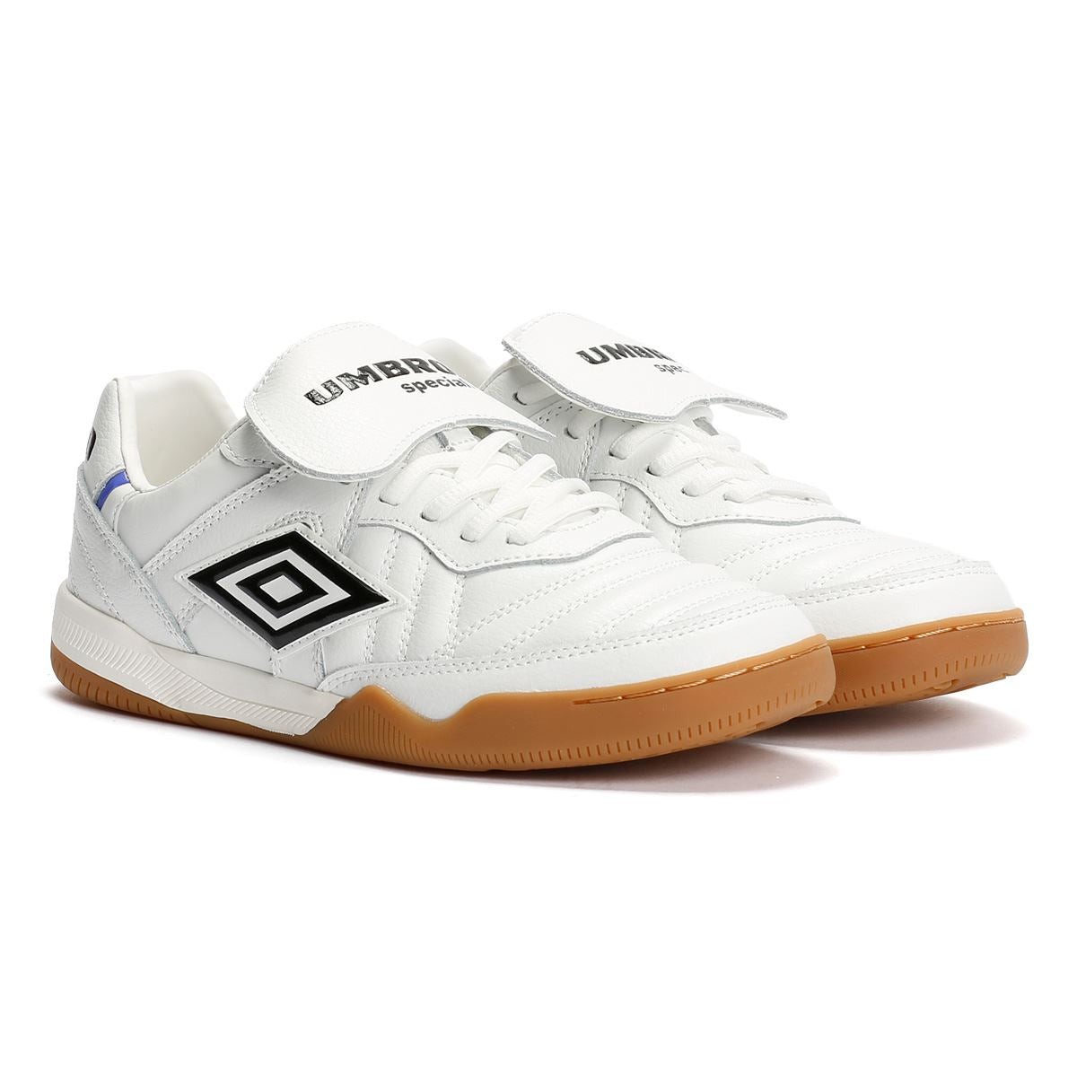 White leather trainers with black and royal blue accents, featuring a flap over the laces, a gum rubber sole, and the Umbro logo prominently displayed on the side.