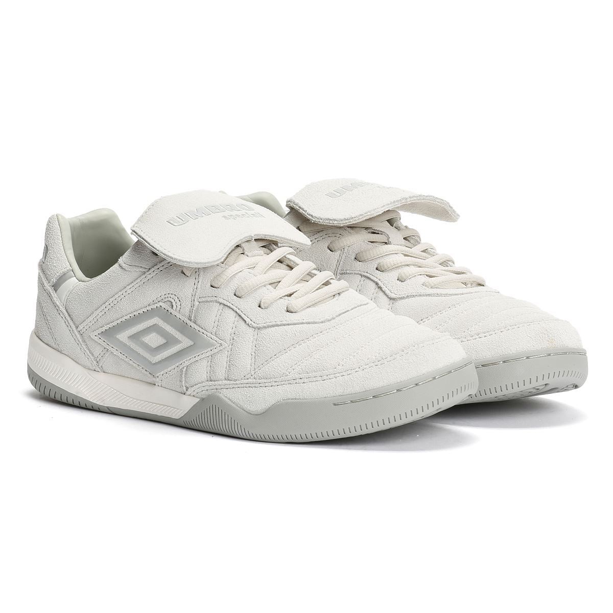 Light grey suede trainers featuring a padded tongue, lace-up front, and a distinctive Umbro logo on the side, with a textured rubber sole for grip.
