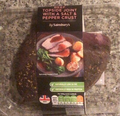 Topside beef joint with a salt and pepper crust, presented on a black plate with vegetables, packaged in a clear plastic tray with a label from Sainsbury's.