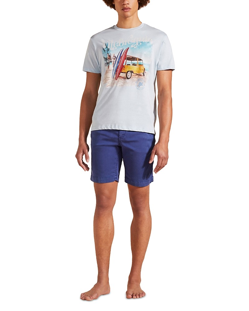 Light blue cotton T-shirt featuring a surf and Mini Moke graphic, paired with navy shorts, model stands barefoot, showcasing a relaxed beach style in size XL.