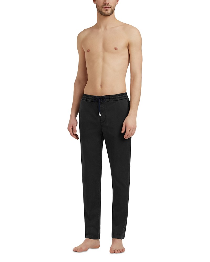 Satin pull-on pants in black with a drawstring waistband, featuring a relaxed fit and straight legs, modeled by a shirtless man standing barefoot.