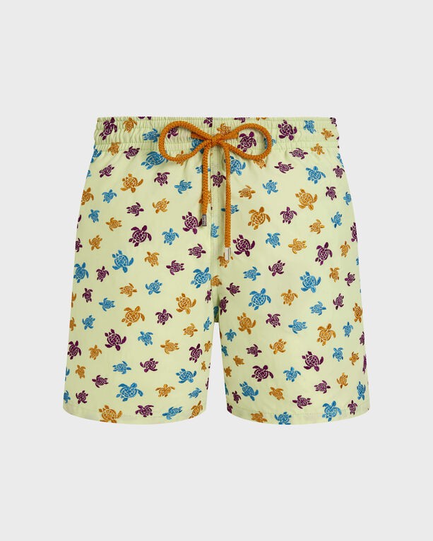 Green swim shorts featuring a colorful embroidered turtle pattern in yellow, blue, and purple, with an elastic waistband and drawstring, made from lightweight material.