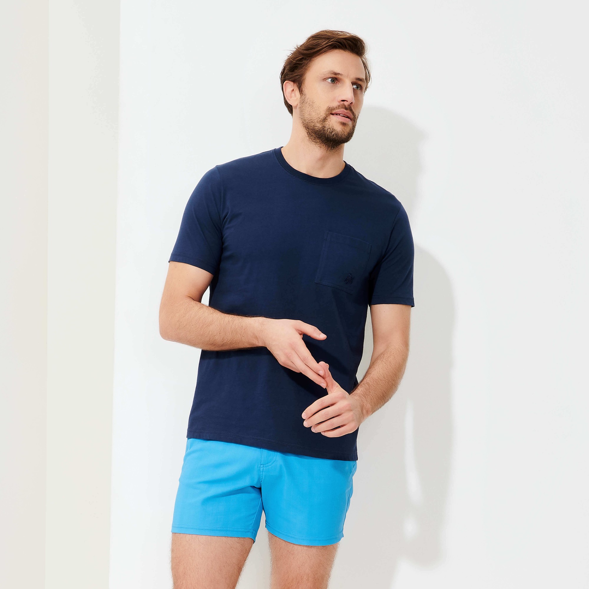 Men's solid blue organic cotton T-shirt by Vilebrequin, featuring a round neckline, short sleeves, and a chest pocket, styled with light blue shorts.