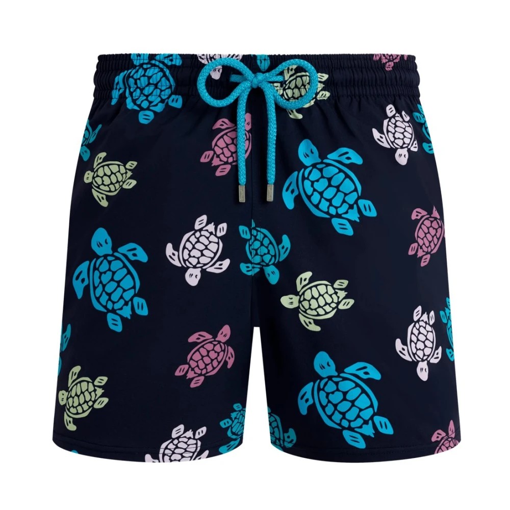 Blue swim trunks featuring a playful turtle pattern in pink, green, and turquoise, with an elastic waistband and drawstring for a comfortable fit, made from lightweight material.
