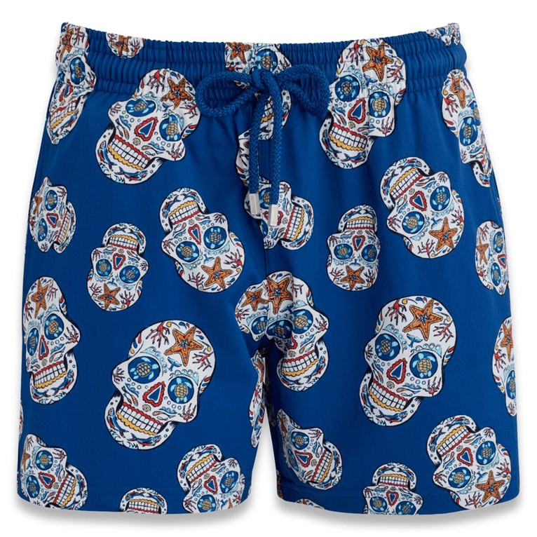 Blue stretch swim trunks featuring a Día De Muertos skull pattern in vibrant colors, with an elastic waistband and drawstring, made from lightweight material, size XXXL.