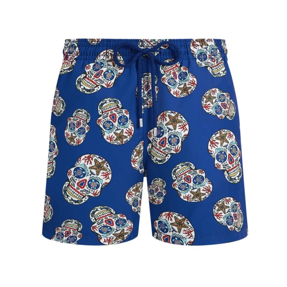 Blue stretch swim trunks featuring a colorful Día De Muertos skull pattern, with a drawstring waist and vibrant coral and floral designs, in size XXL.
