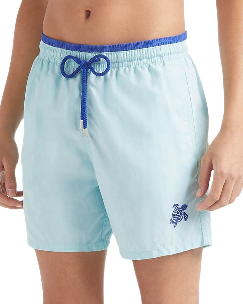 Light blue swim shorts featuring a turtle logo, elastic waistband with a blue drawstring, and a relaxed fit, made from quick-drying material.