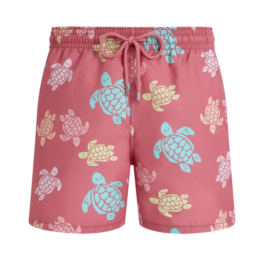 Pink swim shorts featuring a playful multicolored turtle print in yellow and blue, made from lightweight material with an elastic waistband and adjustable drawstring.