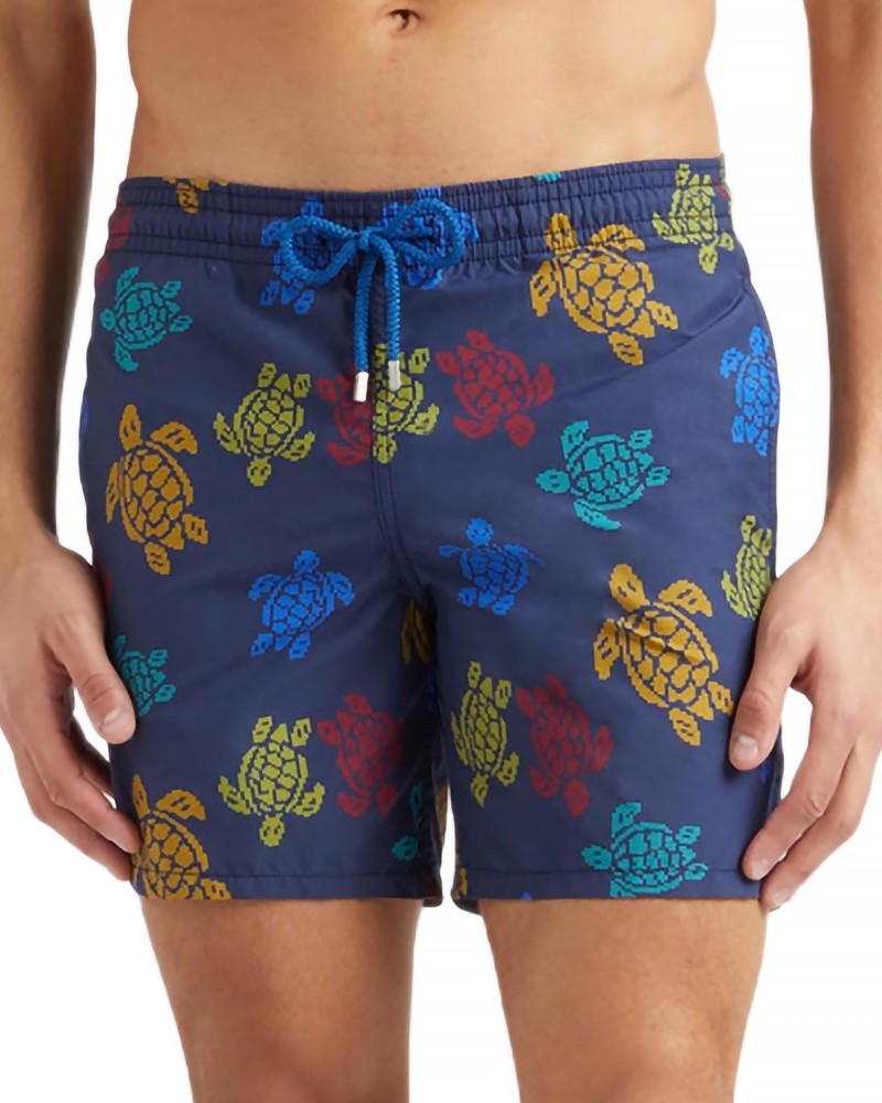 Blue swim shorts featuring colorful turtle patterns in yellow, orange, and green, with an elastic waistband and drawstring for adjustable fit, made from lightweight material.
