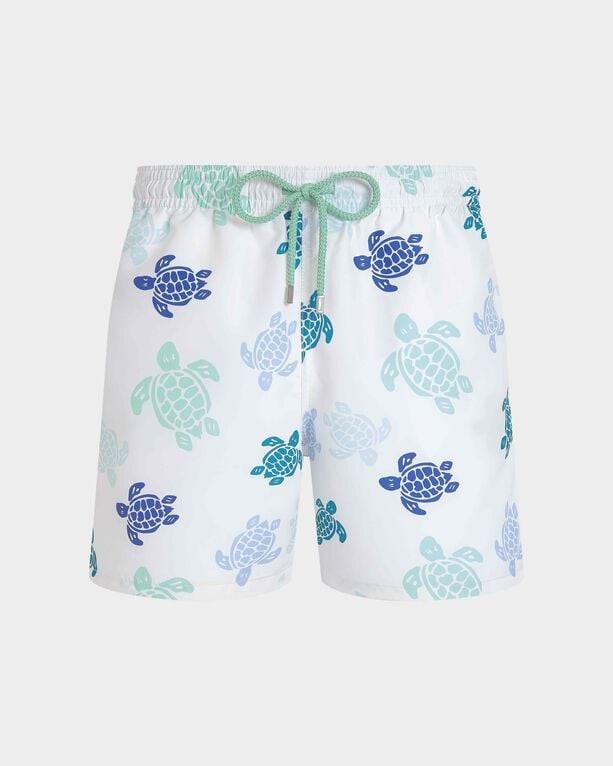 White swim shorts featuring a colorful turtle pattern in shades of blue and green, with an elastic waistband and drawstring, made from lightweight material.
