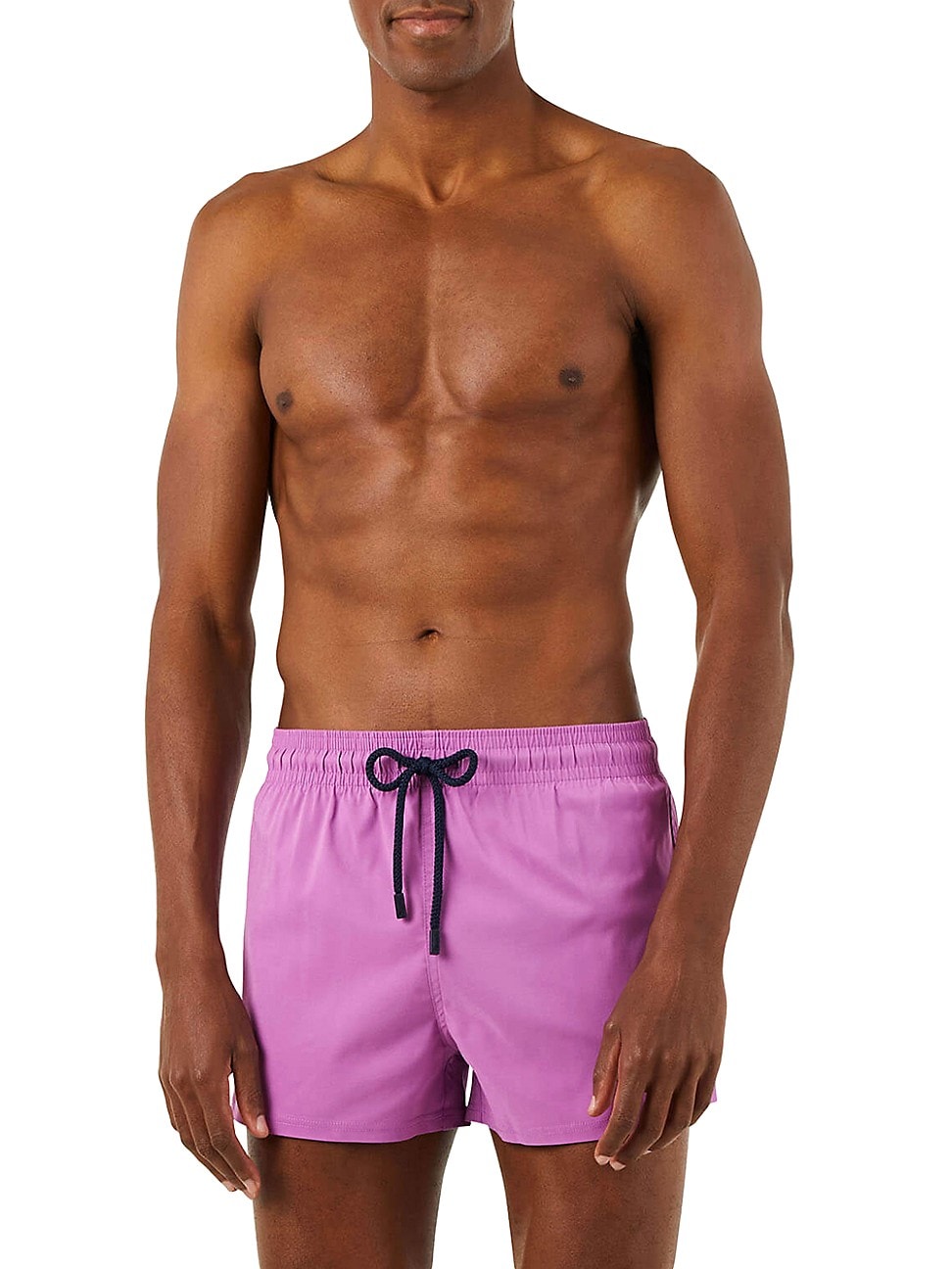 Fitted solid pink swim shorts with an elastic waistband and navy drawstring, modeled by a muscular man with a toned physique, showcasing a stylish beachwear look.