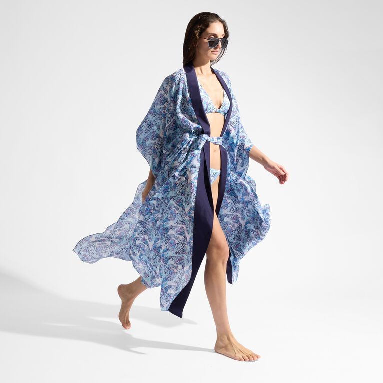 Flowing white silk kimono with a vibrant blue fish print, featuring wide sleeves and a navy tie belt, worn over a bikini, complemented by stylish sunglasses.