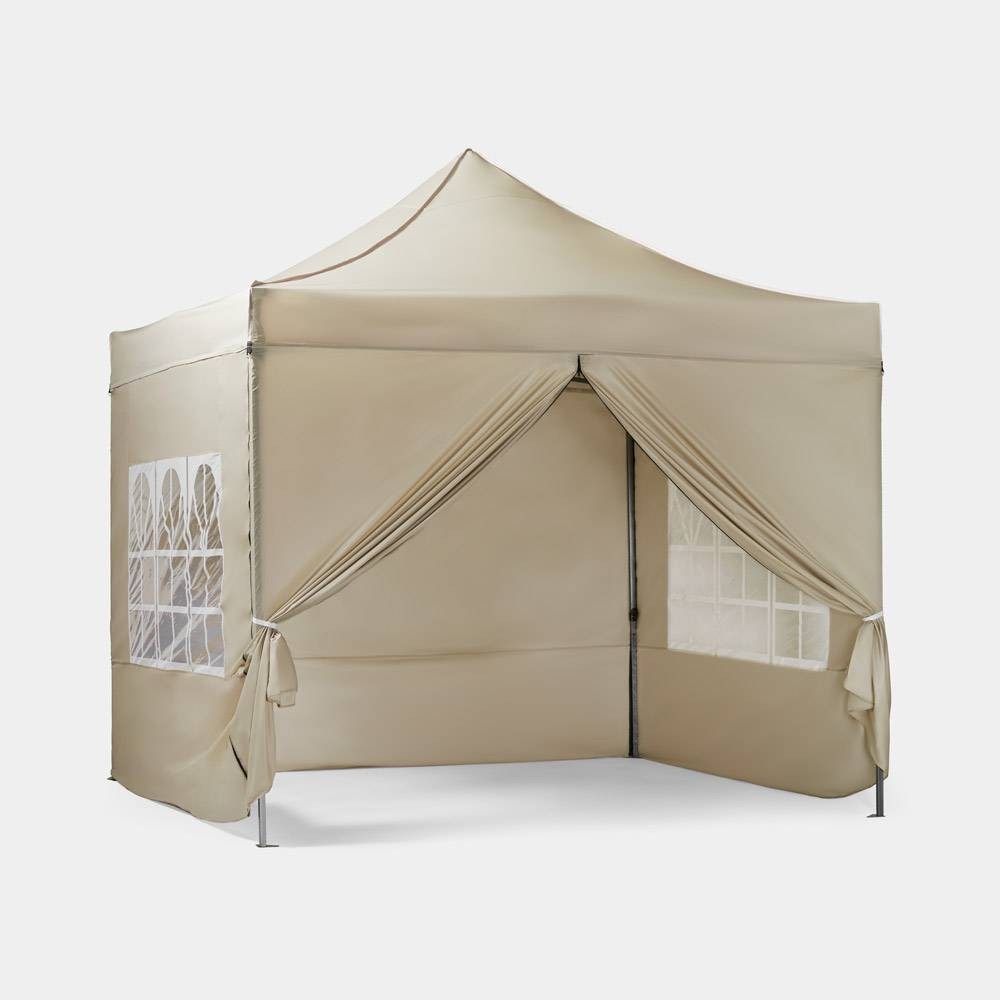 Beige 3m x 3m pop-up gazebo with side walls, featuring large windows and decorative drapes, made from durable fabric with a peaked roof.