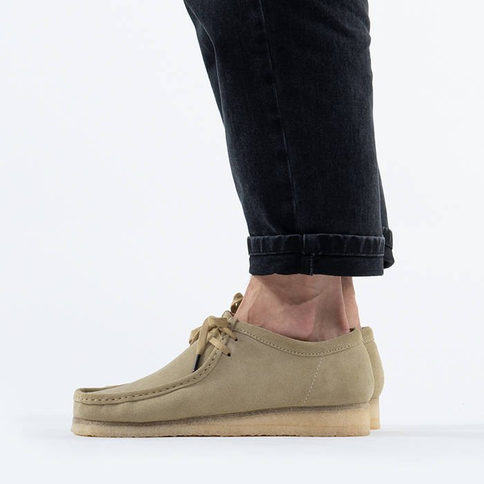 Men's Clarks Originals Wallabee in maple suede, featuring a classic moccasin design, lace-up front, and a natural crepe sole, paired with dark jeans.