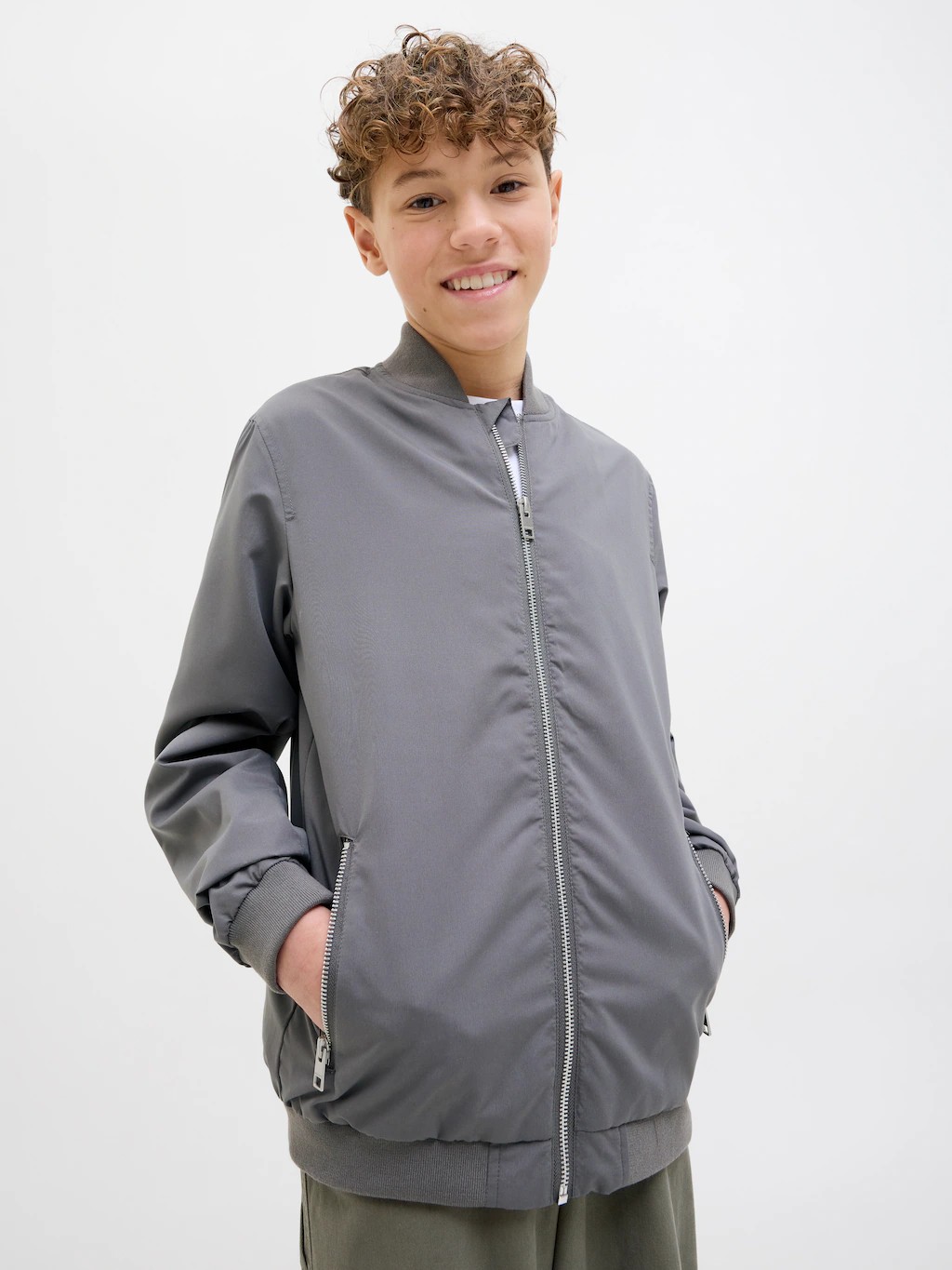 Gray waterproof jacket for children by Jack & Jones, featuring a zip front, ribbed cuffs, and a relaxed fit, perfect for outdoor activities.