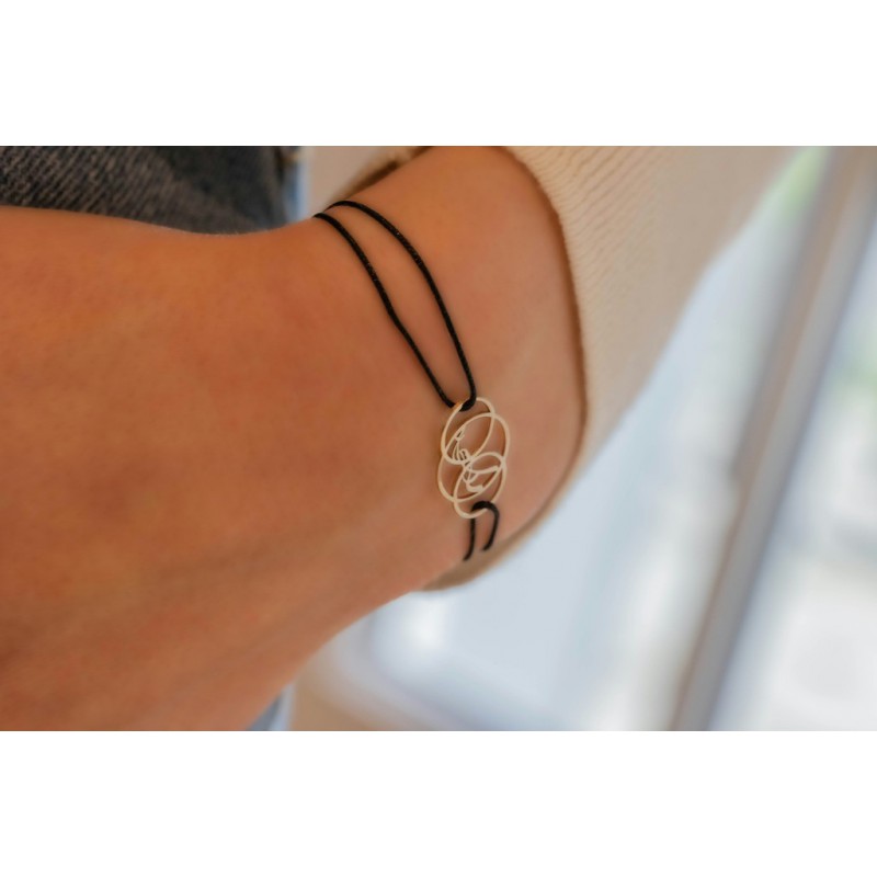 Delicate black cord bracelet featuring a silver floral design, elegantly wrapped around the wrist, showcasing a minimalist and modern aesthetic.
