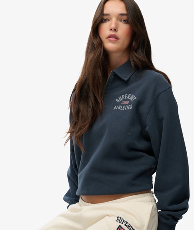 Navy blue cropped sweater with a collared neckline, featuring "Superdry Athletics" logo on the chest, made from soft material, styled with long sleeves.