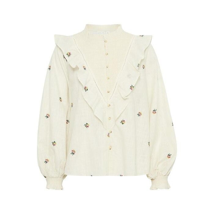 Cream-colored women's blouse with a ruffled front, floral embroidery, and button closure, featuring long puff sleeves and a high neckline.