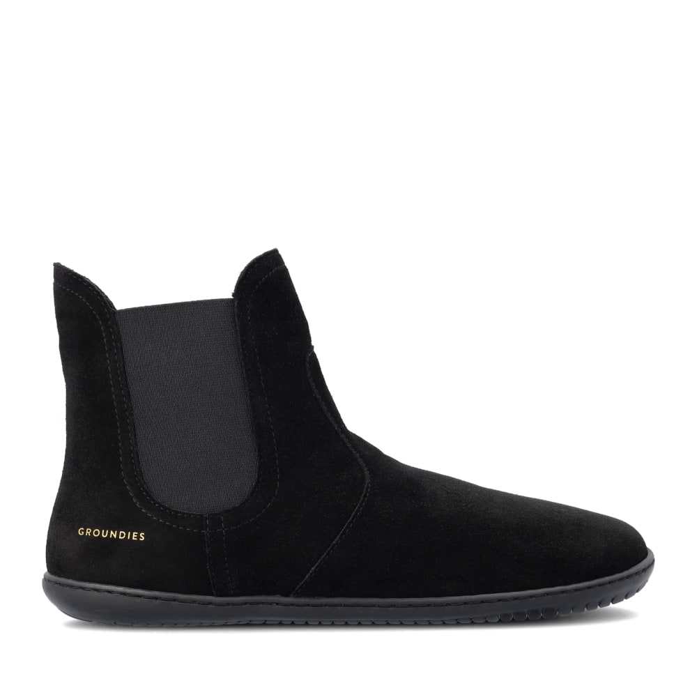 Black suede women's boots with elastic side panels, featuring a minimalist design and a flexible sole, branded with "GROUNDIES" in gold on the heel.