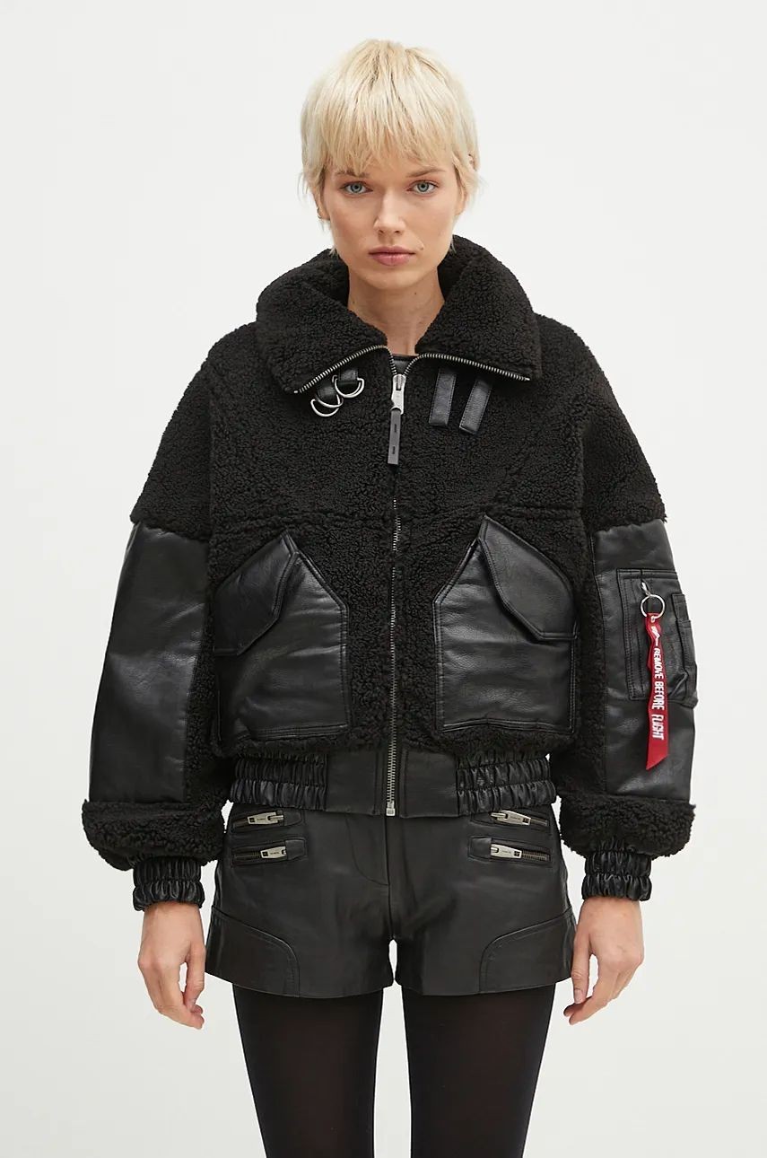 Black teddy coat with leather accents, featuring a zip front, oversized collar, and unique pocket details, styled with a model wearing leather shorts.