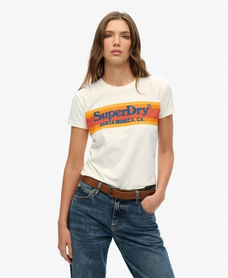 White fitted T-shirt featuring a colorful retro Superdry logo in orange and yellow, made from soft cotton, paired with high-waisted blue jeans.