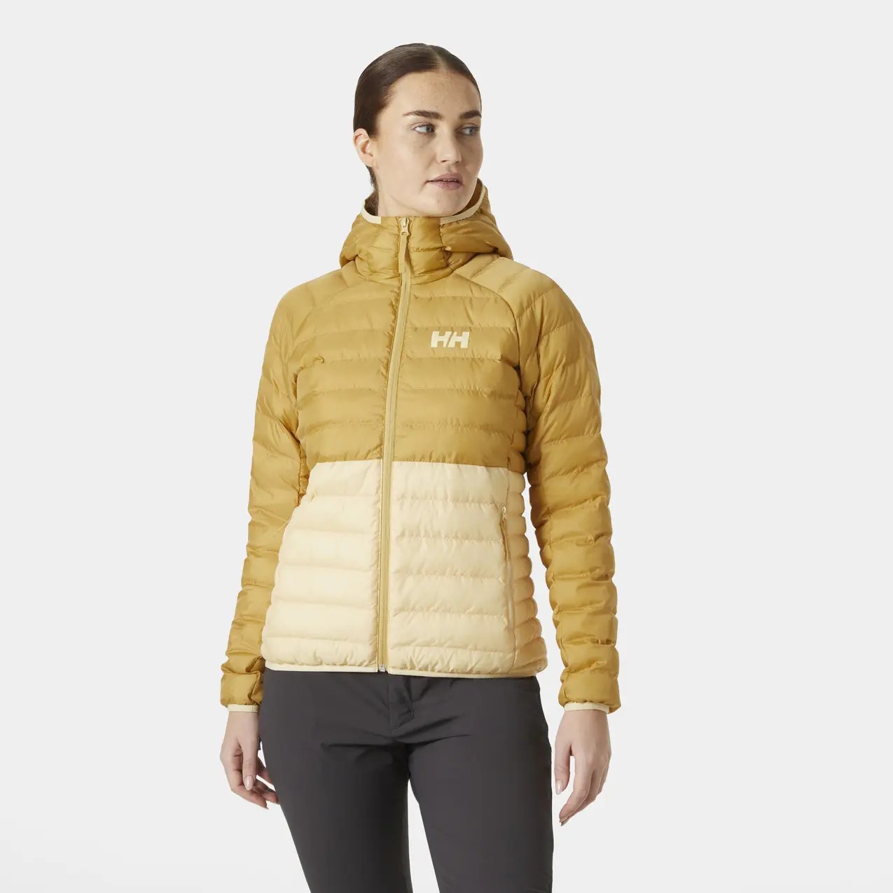 Women's Helly Hansen Banff insulated hooded puffer jacket in mustard yellow and cream, featuring a zip front, quilted design, and logo on the chest.