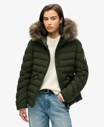 Green padded jacket with a faux fur hood, featuring a zip front, ribbed cuffs, and a relaxed fit, worn over a cream sweater and light blue jeans.