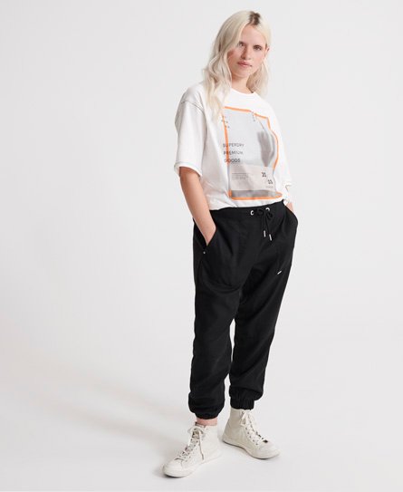 Black Tencel sweatpants with a relaxed fit, featuring an elastic waistband, drawstring, and cuffed ankles, paired with a white graphic tee and white sneakers.