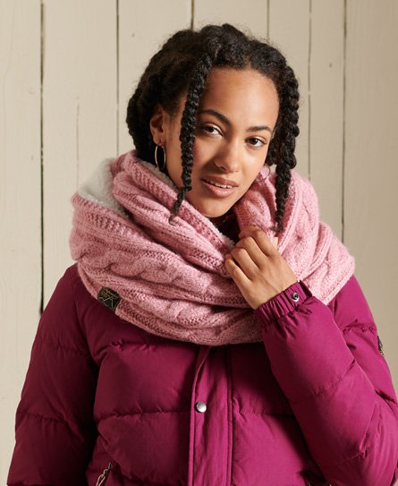Pink knitted snood with a textured cable pattern, featuring a soft lining, worn by a woman with curly hair, paired with a maroon puffer jacket.