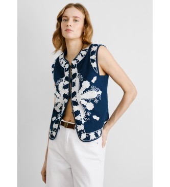 Navy blue sleeveless vest by Pepe Jeans featuring intricate white floral embroidery and a front zipper, styled with a white belt and light-colored pants.