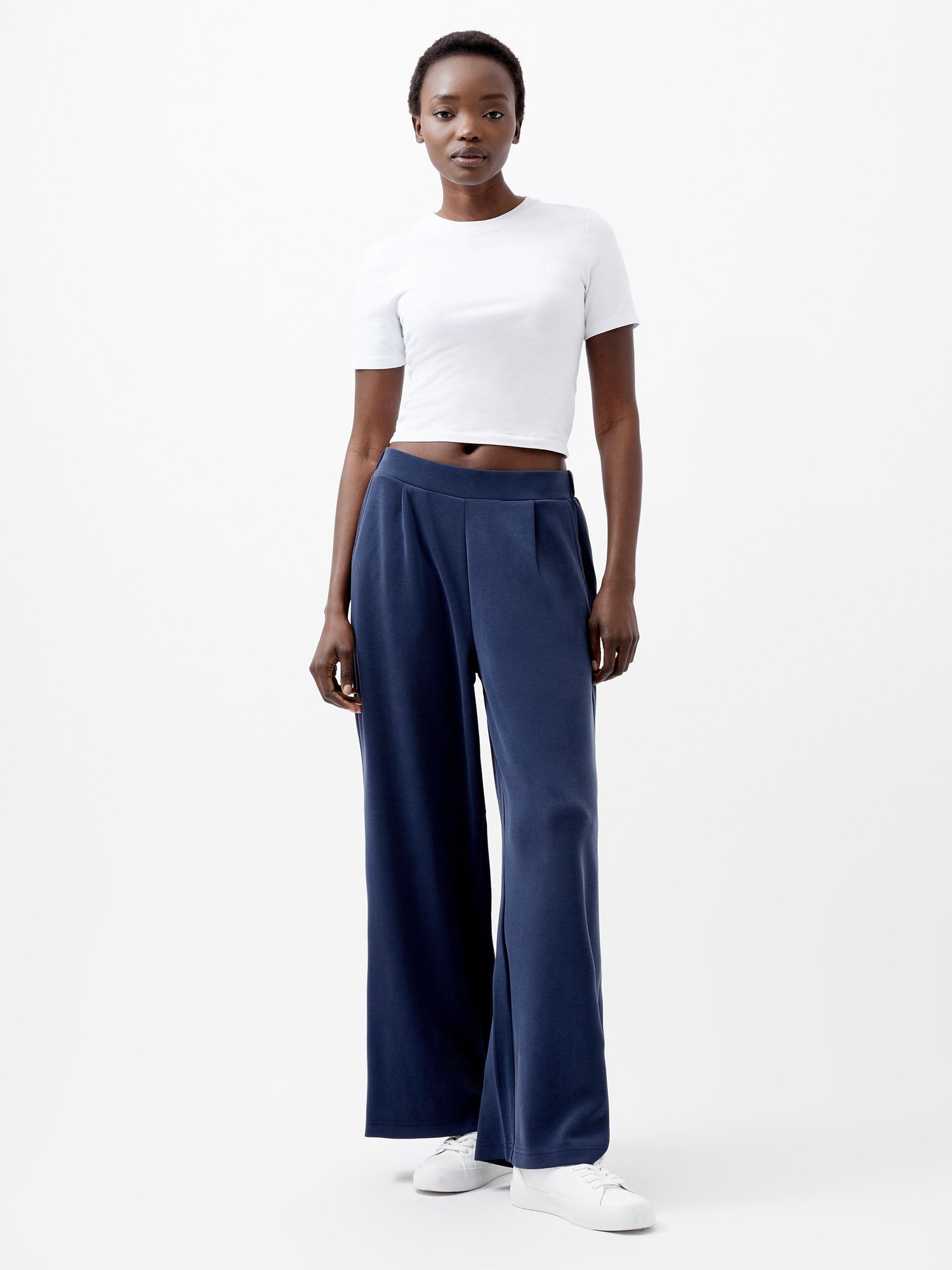 Midnight blue wide leg trousers by French Connection, featuring a high waist, soft fabric, and a relaxed fit, styled with a white cropped t-shirt and white sneakers.