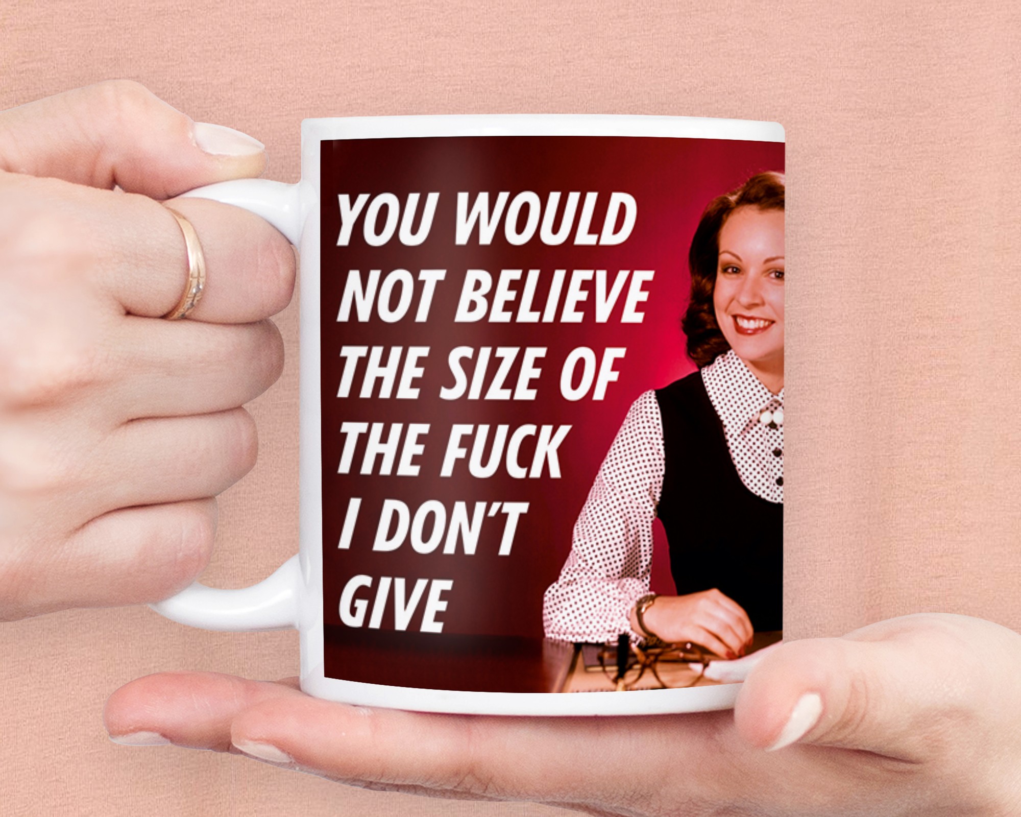 A white ceramic mug featuring bold black text that reads "YOU WOULD NOT BELIEVE THE SIZE OF THE FUCK I DON'T GIVE," with a smiling woman in a black outfit and white blouse.