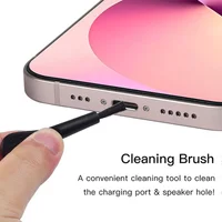 Black cleaning brush tool inserted into a smartphone charging port, with a pink screen and silver edges.