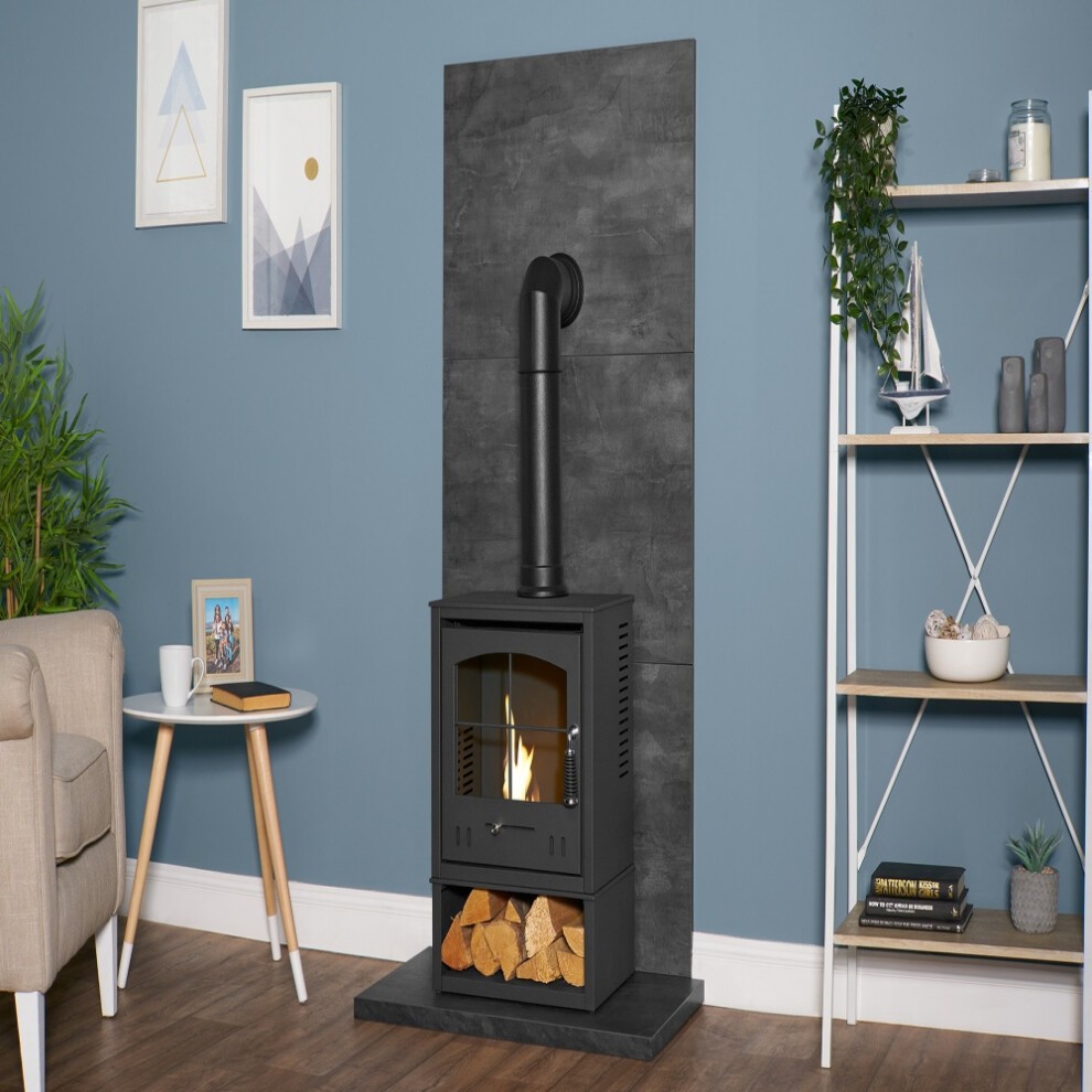 Slate Venetian plaster effect wall with a black OKO S2 stove, log store, and tall angled pipe, complemented by a light-colored armchair and decorative shelving.