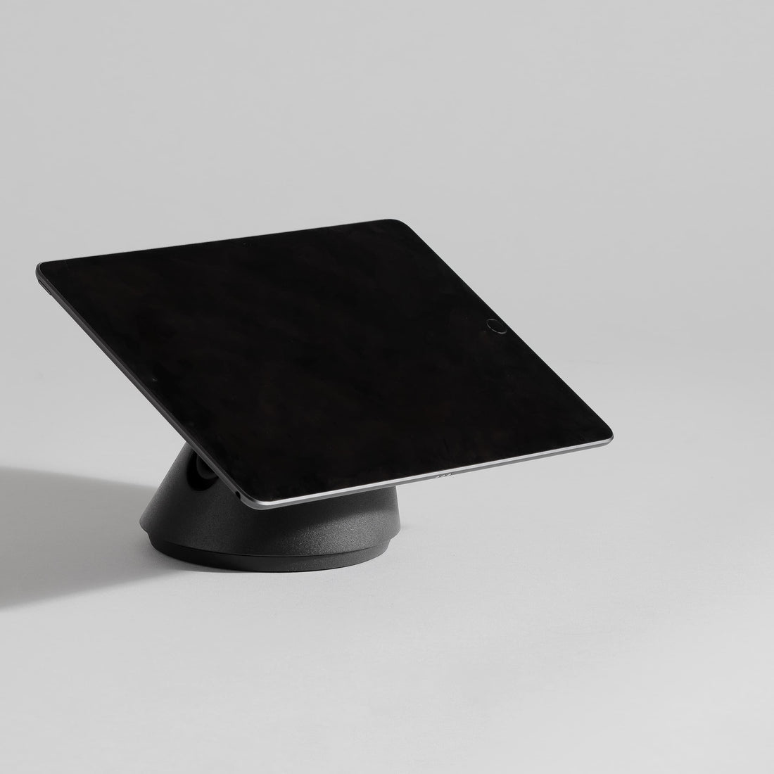 Black, sleek tablet stand with a secure docking base, designed for iPads, featuring an adjustable angle for optimal viewing.