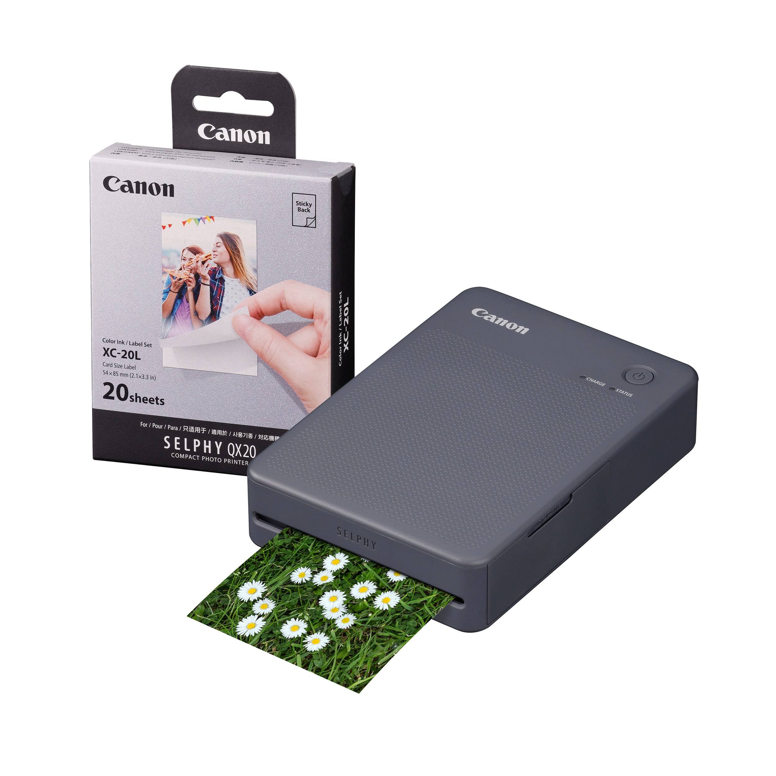Canon Selphy QX20 instant photo printer in dark grey, featuring a textured surface, compact design, and a box containing 20 photo sheets, with a print of daisies emerging from the front.