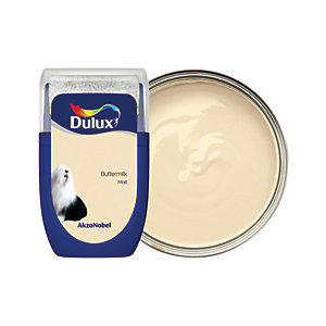 Dulux Colour Tester in Buttermilk, 30ML, features a creamy beige paint with a smooth texture, housed in a clear container with a blue label and a silver lid.