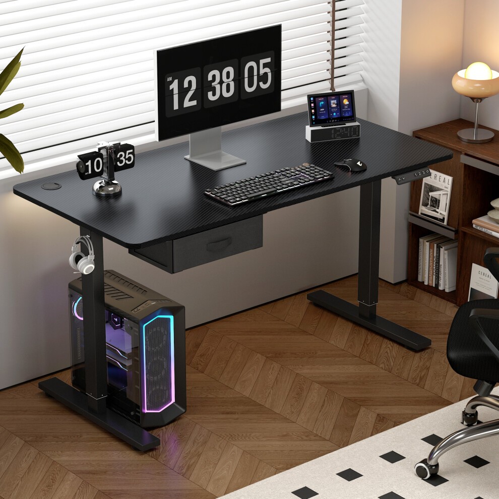 Black adjustable electric computer desk with a sleek design, featuring a drawer, a monitor, and a gaming PC with RGB lighting, set against a bright window and stylish decor.