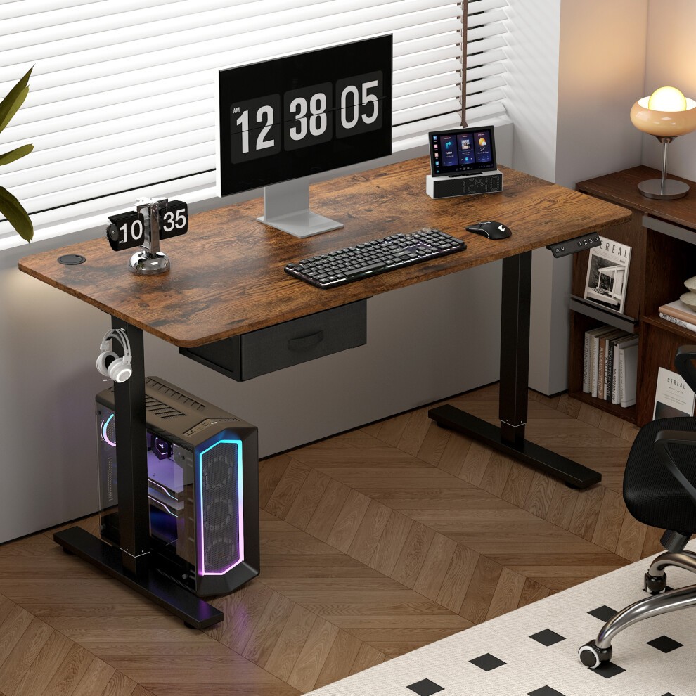 Brown adjustable electric computer desk by MCC, featuring a wood-like surface, black metal legs, a built-in drawer, and a modern design with a monitor and gaming PC setup.