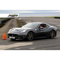 Black Ferrari supercar driving on a track, sleek design, orange traffic cone nearby, PSR Experience logo in corner.