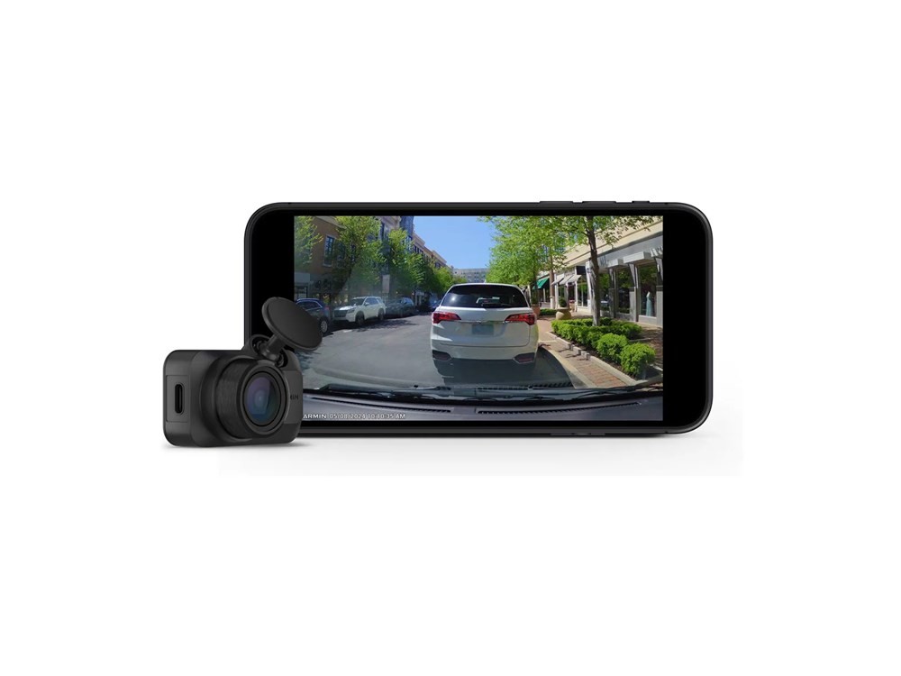 Compact black Garmin Dash Cam Mini 3 with a lens and flip-up cover, positioned next to a smartphone displaying a street view captured by the camera.