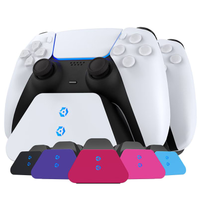 White Gioteck PS5 Duo Charging Stand with two PS5 controllers, featuring a sleek design and LED indicators for charging status, set against a colorful array of interchangeable base colors.