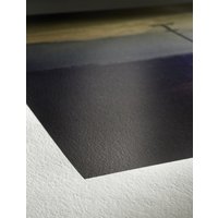 Hahnemühle A4 satin-matt photo paper, smooth texture, subtle sheen, corner detail on wooden surface.