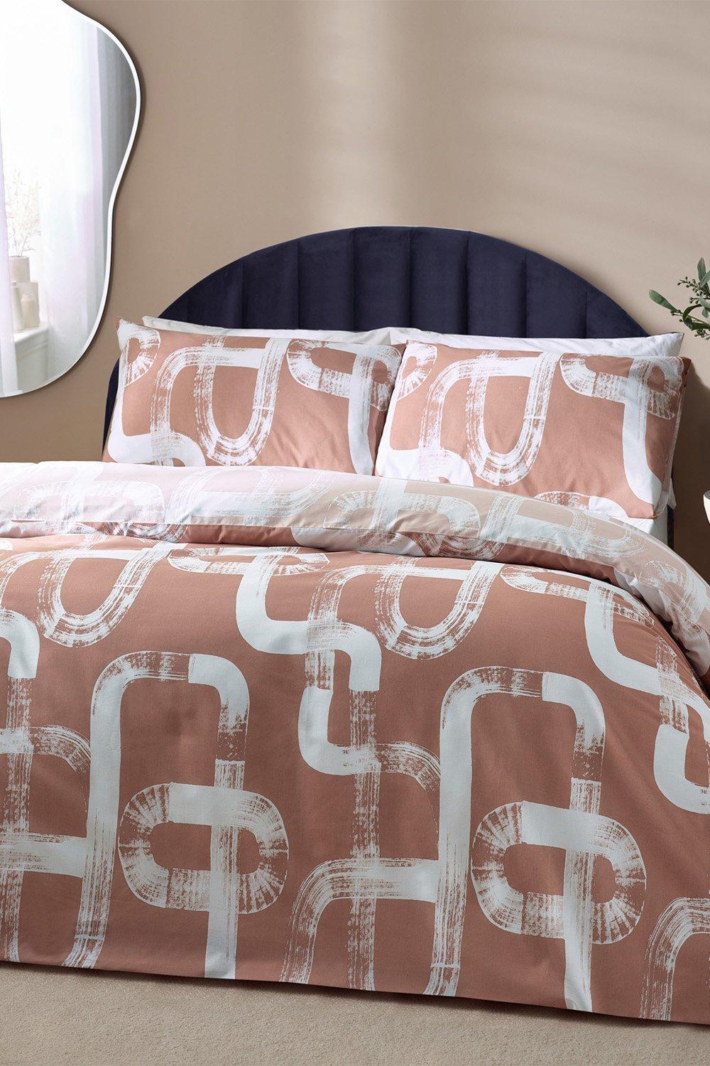 Pink cotton-rich reversible duvet cover set featuring an abstract white pattern, complemented by matching pillowcases, designed for a king-sized bed.