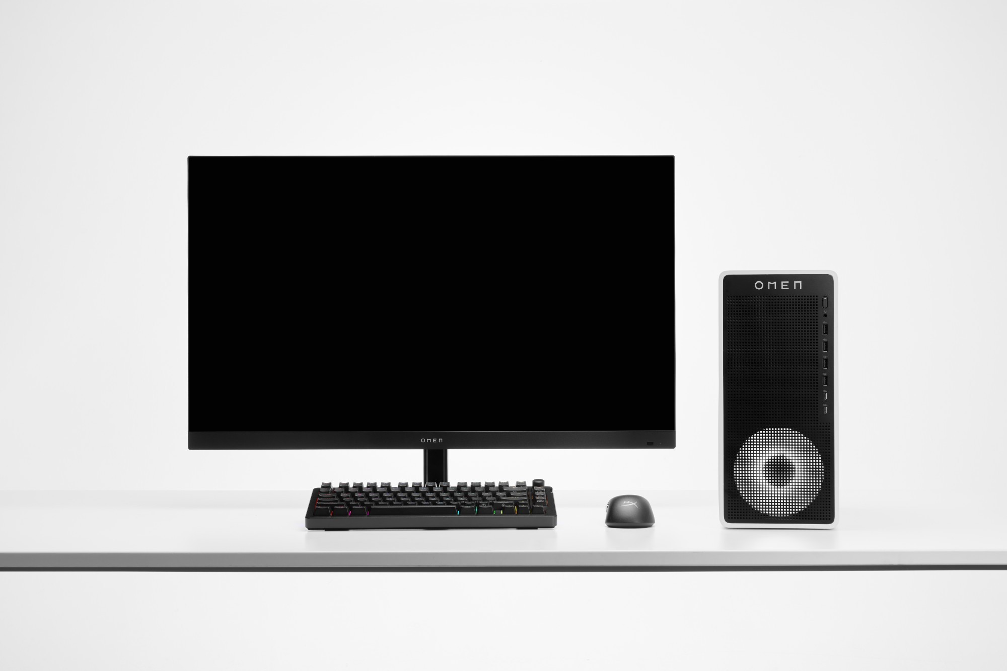 Sleek black HP OMEN desktop setup featuring a monitor, a compact tower with a mesh front panel, a mechanical keyboard with RGB lighting, and a matching mouse on a white desk.