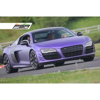 Purple Audi R8 V10 on a racetrack, sleek design, black grille, and alloy wheels, part of a driving experience package.