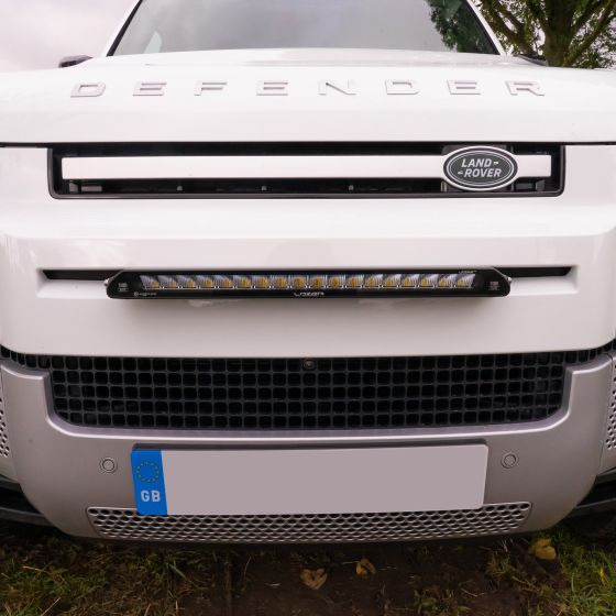 Lazer Lamps Grille Integration Kit featuring a sleek black Linear 18 Elite Lamp mounted on a white Land Rover Defender's front grille.