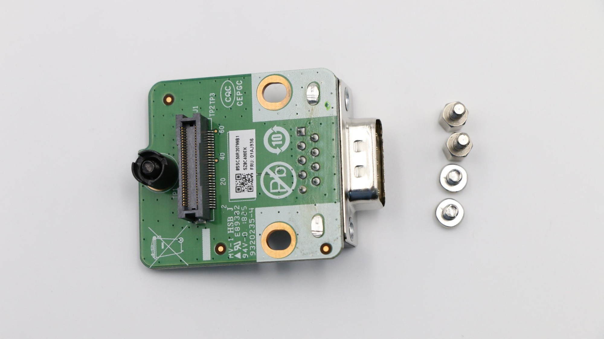 Green circuit board with a metal connector, featuring a small camera lens and three silver screws nearby, labeled with various technical markings and logos.